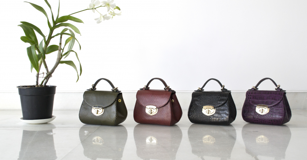 Set of leather bags with two handles, sitting on a wooden table.